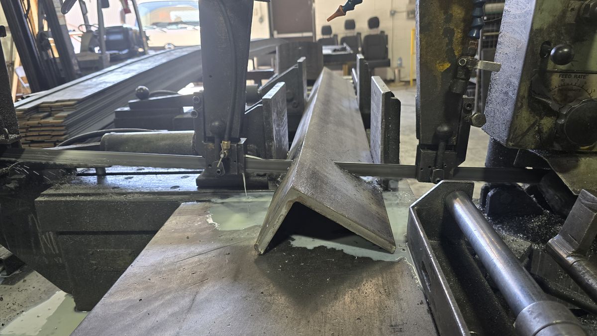 Band saw blade cutting steel angle with coolant